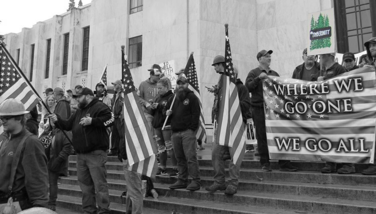 Timber Unity supporters hold up a QAnon flag, representing a dangerous conspiracy theory