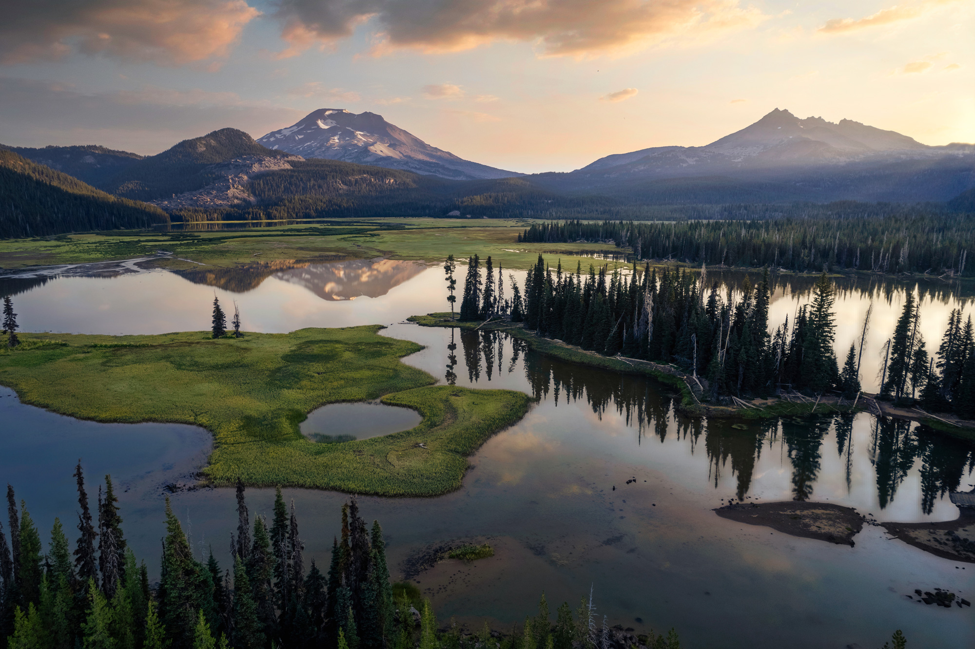 Mountainous landscape with trees reflecting in a lake at dusk