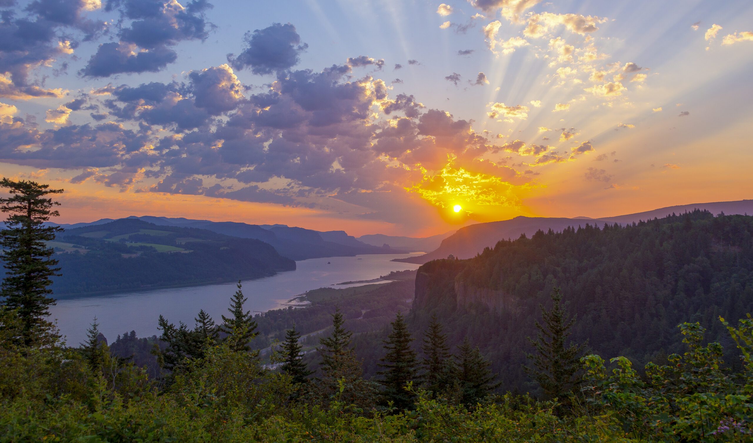 Just to the right of center below the sun you can see the Vista House, an observatory at Crown Point in Multnomah County, Oregon, that also serves as a memorial to Oregon pioneers and as a comfort station for travelers on the Historic Columbia River Highway. This shot was taken from Portland Women's Forum State Scenic Viewpoint.